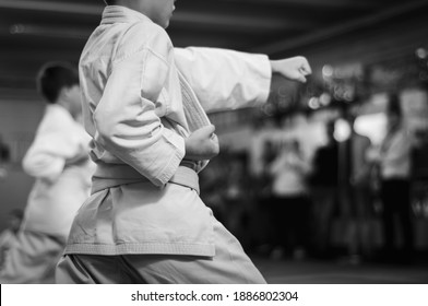 Kids training on karate-do.  Direct punch training. Sports training and a healthy lifestyle.  Black and white  Photo without faces. (focus on the shape on the left. On the right, space for text)