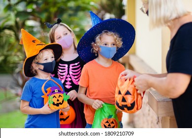 Kids trick or treat in Halloween costume and face mask. Children in dress up with candy bucket in coronavirus pandemic. Little boy and girl trick or treating with pumpkin lantern. Autumn holiday fun.