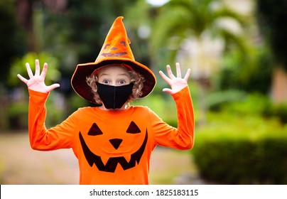 Kids Trick Or Treat In Halloween Costume And Face Mask. Children In Dress Up With Candy Bucket In Coronavirus Pandemic. Little Boy And Girl Trick Or Treating With Pumpkin Lantern. Autumn Holiday Fun.