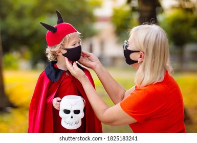 Kids Trick Or Treat In Halloween Costume And Face Mask. Children In Dress Up With Candy Bucket In Coronavirus Pandemic. Little Boy And Girl Trick Or Treating With Pumpkin Lantern. Autumn Holiday Fun.