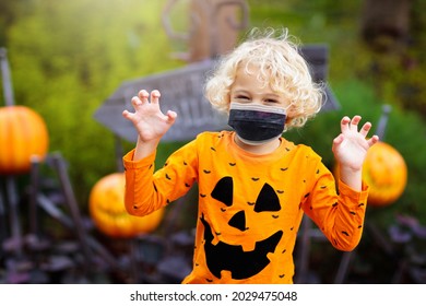 Kids Trick Or Treat In Halloween Costume And Face Mask. Children In Dress Up With Candy Bucket In Coronavirus Pandemic. Little Boy And Girl Trick Or Treating With Pumpkin Lantern. Autumn Holiday Fun.