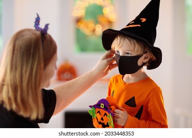 Kids Trick Or Treat In Halloween Costume And Face Mask. Child And Mother In Dress Up With Candy Bucket In Coronavirus Pandemic. Little Boy Trick Or Treating With Pumpkin Lantern. Autumn Holiday Fun.