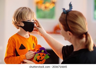 Kids Trick Or Treat In Halloween Costume And Face Mask. Child And Mother In Dress Up With Candy Bucket In Coronavirus Pandemic. Little Boy Trick Or Treating With Pumpkin Lantern. Autumn Holiday Fun.