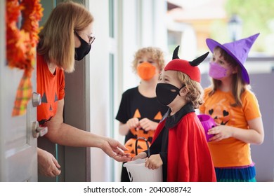 Kids Trick Or Treat In Halloween Costume And Face Mask. Children In Dress Up With Candy Bucket In Coronavirus Pandemic. Little Boy And Girl Trick Or Treating With Pumpkin Lantern. Autumn Holiday Fun.