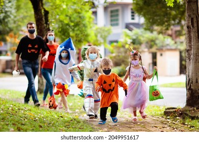 Kids Trick Or Treat In Halloween Costume And Face Mask. Children In Dress Up With Candy Bucket In Coronavirus Pandemic. Little Boy And Girl Trick Or Treating With Pumpkin Lantern. Autumn Holiday Fun.