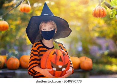 Kids Trick Or Treat In Halloween Costume And Face Mask. Children In Dress Up With Candy Bucket In Coronavirus Pandemic. Little Boy Trick Or Treating With Pumpkin Lantern. Autumn Holiday Fun.