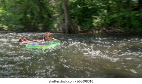 Kids Tubing Down River On Hot Summer Day