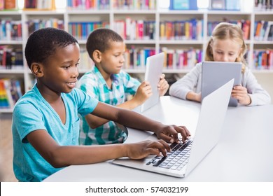 Kids Using Laptop And Digital Tablet In Library At School