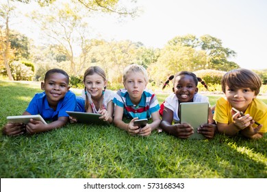 Kids using technology during a sunny day at park - Powered by Shutterstock