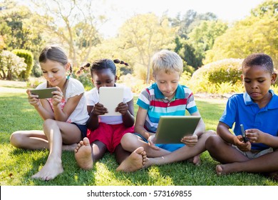 Kids Using Technology During A Sunny Day At Park