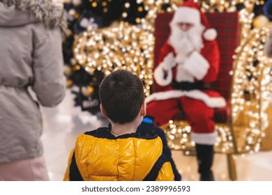 Kids waiting to meet and see Santa Claus, children asking Santa Claus for a gift on Christmas fair market in a shopping mall trade center, boys and girls visit Santa and receive gifts and presents - Powered by Shutterstock