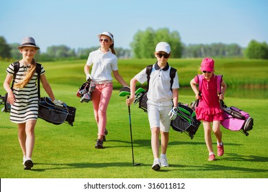 Kids walking on fairway with bags at golf school 
