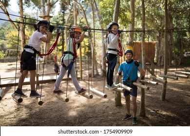 Kids Walking On Rope Bridge In Park On A Sunny Day