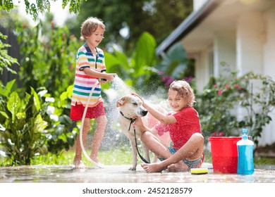 Kids wash dog in summer garden. Water hose and sprinkler fun for kid. Children washing puppy on outdoor patio in blooming backyard. Kids play. Child with pet. Family bathing dog. Animal care. - Powered by Shutterstock