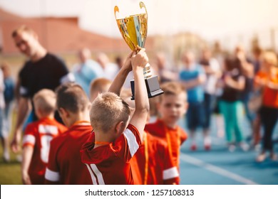 Kids Winning Sports Competition. Children Soccer Team With Trophy. Boys Celebrating Football Championship In Primary School Fooutball Tournament