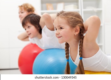 Kids and woman doing gymnastic exercises with balls - stretching their back