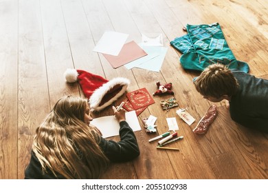 Kids Writing Christmas Cards On Wooden Floor