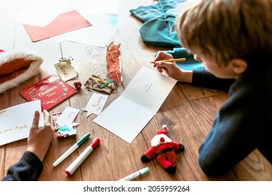 Kids Writing Christmas Cards On Wooden Floor