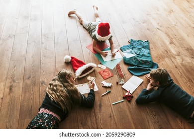 Kids Writing Christmas Cards On Wooden Floor