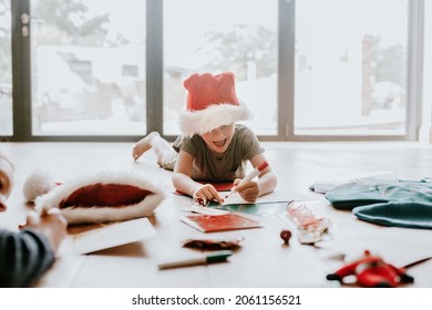 Kids Writing Christmas Cards On Wooden Floor