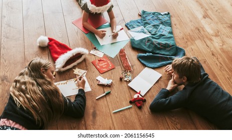 Kids Writing Christmas Cards On Wooden Floor