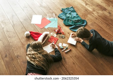 Kids Writing Christmas Cards On Wooden Floor