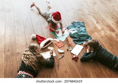 Kids Writing Christmas Cards On Wooden Floor