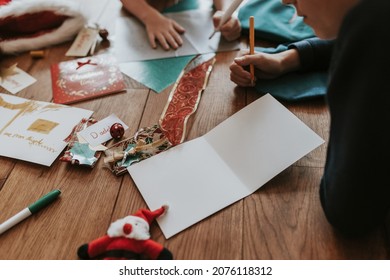 Kids Writing Christmas Cards On Wooden Floor