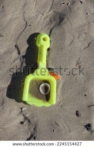 kids yellow plastic shovel with shell on tha sand beach