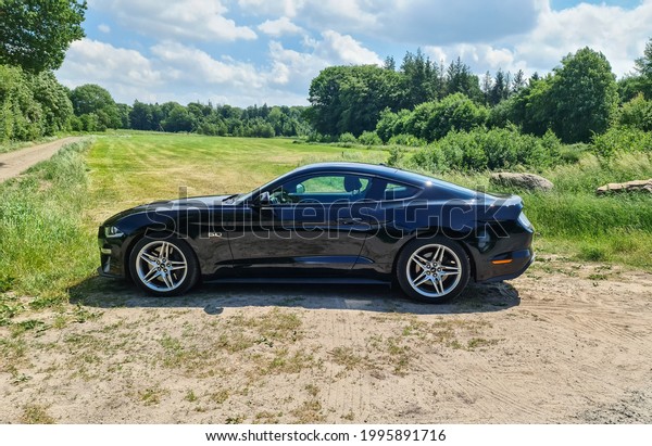 KIEL,\
GERMANY - Jun 19, 2021: Side view on a black Ford Mustang Model\
2018 in front of a northern germany\
landscape