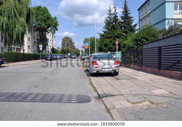 Kielce, Świętokrzyskie / Poland 2020-08-19 Cars\
parked on the sidewalk and residential buildings by the road (part\
of registration\
erased)\
