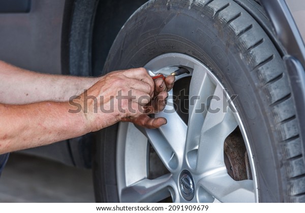 Kiev, September 12, 2021.Car mechanic changing\
wheels in car.Man filling air in the tires of his car (inflating\
tire).Mechanic changing tire in car service center. Transport\
maintenance detail.