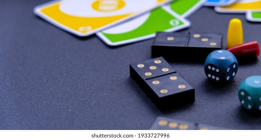 Kiev Ukraine - 10.03.21 Dice, Dominoes Uno Playing Cards On Black Background. Table Games. Stay Home Activity For Kids Family.