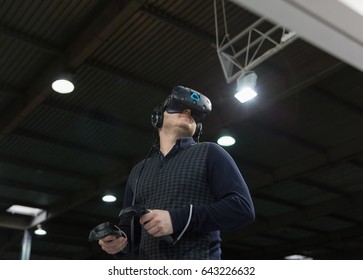 KIEV, UKRAINE - APRIL 07, 2017: Man Use Virtual Reality Game Glasses And Hand Controllers At 2nd International Trade Show Of Electric And Hybrid Vehicles Plug-In Ukraine In KyivExpoPlaza Venue.