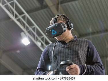 KIEV, UKRAINE - APRIL 07, 2017: Man Use Virtual Reality Game Glasses And Hand Controllers At 2nd International Trade Show Of Electric And Hybrid Vehicles Plug-In Ukraine In KyivExpoPlaza Venue.