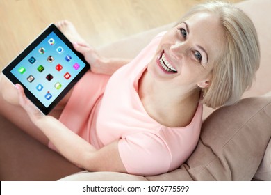 Kiev, Ukraine - April 14, 2016: Woman Working On A Brand New Black Apple IPad Developed By Apple Inc. Middle Aged Woman Sitting On Couch With Black Apple IPad And Looking Up. Unusually Top View