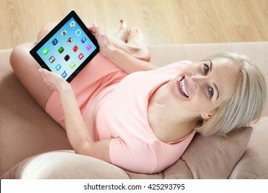 Kiev, Ukraine - April 14, 2016: Woman Working On A Brand New Black Apple IPad  Developed By Apple Inc. Middle Aged Woman Sitting On Couch With  Black Apple IPad And Looking Up. Unusually Top View