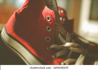 Kiev, Ukraine - April 2, 2020: Red Converse Sneakers. Sneakers. Red Colored Covers Are Near The Window. Vintage Photo Processing.