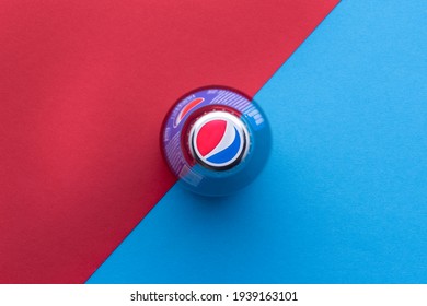 Kiev, Ukraine - February 14, 2021: Cap with the logo of the American brand Pepsi. Glass bottle 0.25 l stands on a red-blue background top view