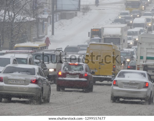 Kiev, Ukraine - January 2019: Stream of cars on the\
snow track. Traffic jam on the snowy road. Car moving on a snowy\
road in the city.