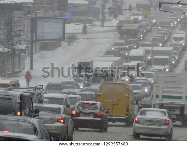 Kiev, Ukraine - January 2019: Stream of cars on the\
snow track. Traffic jam on the snowy road. Car moving on a snowy\
road in the city.