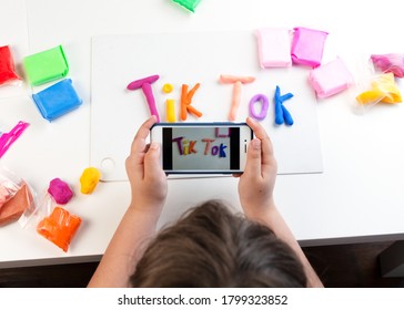 Kiev, Ukraine - June 2020: A Young Teenage Girl Holds A Phone And Shoots Content For Social Networks. On The Table Are Multicolored Letters Tik Tok