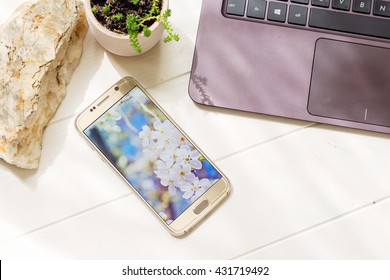 KIEV, UKRAINE - JUNE 4, 2016: Gold Samsung Galaxy S6 With Nature Wallpaper On The Screen. Still Life Mock Up With Smartphone With 1440 X 2560 Pixels Display Resolution