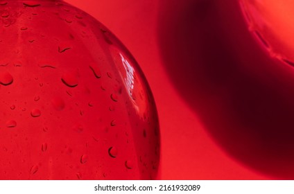 Kiev, Ukraine - May 20, 2022: Bubble With Drops Inside And Reflection Of A Red Cap Of Coca-Cola, Which Stands Next To A Bottle Of Drink On A Red Background