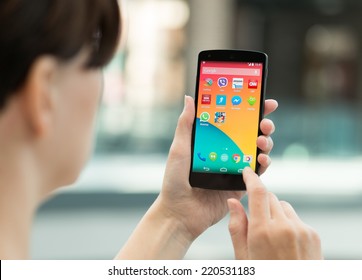 Kiev, Ukraine - September 14, 2014: Woman using a brand new Google Nexus 5 outdoors. Google Nexus 5 is powered by Android 4.4 version, manufactured by LG Electronics.