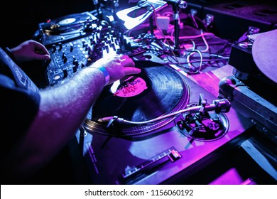 KIEV-4 JULY,2018: Dj Panchez Scratches Vinyl Records On Retro Technics SL Turntable Player Device In Night Club On Party.Overhead View Of Djs Turn Tables At Concert Stage In Blue And Magenta Lights