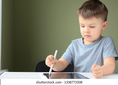 Kiev/Ukraine - 02.26.2019 White caucasian smiling toddler boy drawing on the screen of iPad Pro with white pencil. Portrait of happiness cute little boy with tablet. Boy playing game on tablet
