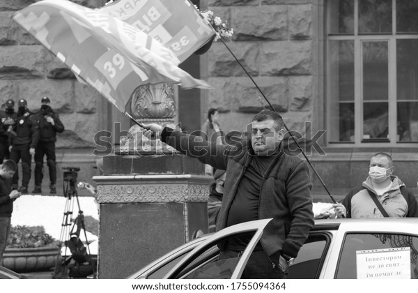 Kiev/Ukraine - 05.29.2020: black white\
photo of middle aged person standing on the street near the car\
waving flag at political protest anti government\
rally