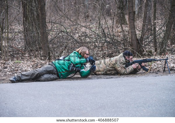KIEV,UKRAINE - March 26 :\
Photographer lying on ground near volunteer with weapon during\
military training \