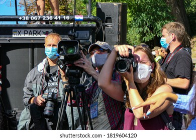 Kiev/Ukraine - September 14, 2020: man reporter operator with videocamera and woman professional photographer with photo camera filming people at street protest rally. Faces with protective masks